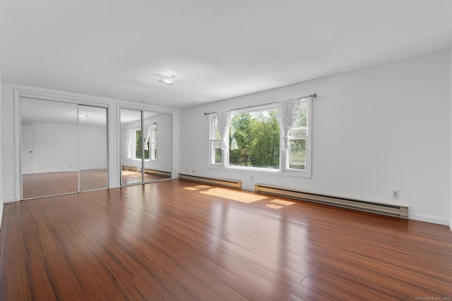 130 Fitch St, North Haven, CT 06473 - unfurnished bedroom with a baseboard heating unit, multiple closets, and wood finished floors