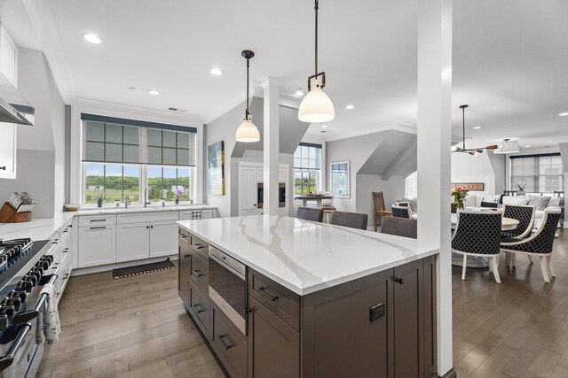 66 High St Unit 40, Guilford, CT 06437 - kitchen featuring appliances with stainless steel finishes, open floor plan, ornamental molding, wood finished floors, and light stone counters