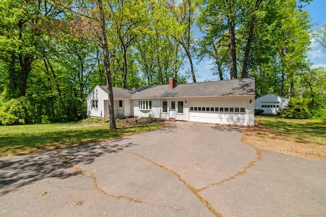 single story home featuring a garage, a chimney, a front yard, and asphalt driveway