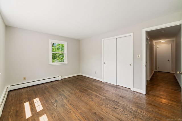 unfurnished bedroom with a baseboard radiator, dark wood finished floors, baseboards, and a closet