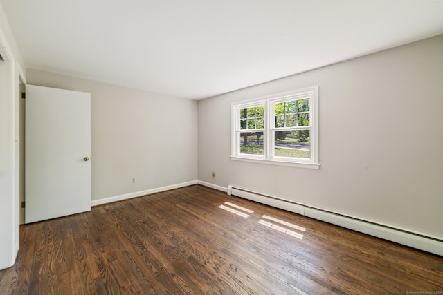 spare room with a baseboard heating unit, wood finished floors, and baseboards