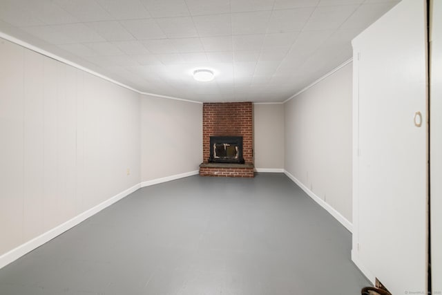 finished basement featuring a brick fireplace, crown molding, and baseboards