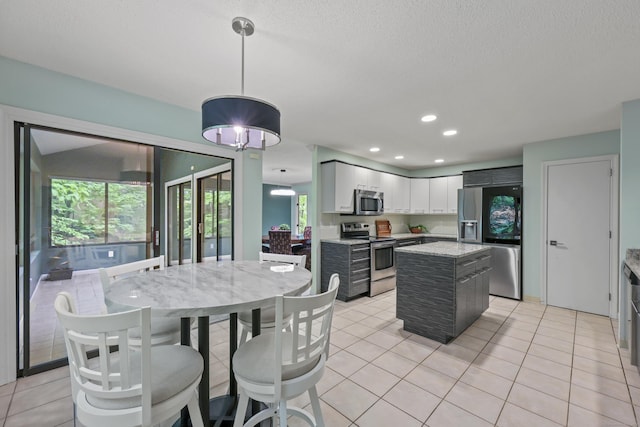 114 Mountain View Rd, Glastonbury, CT 06033 - kitchen featuring appliances with stainless steel finishes, a kitchen island, hanging light fixtures, light tile patterned floors, and light stone countertops