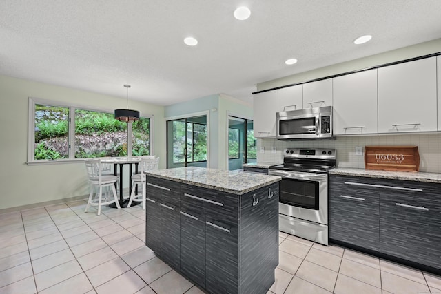 114 Mountain View Rd, Glastonbury, CT 06033 - kitchen with stainless steel appliances, dark cabinetry, white cabinetry, backsplash, and plenty of natural light