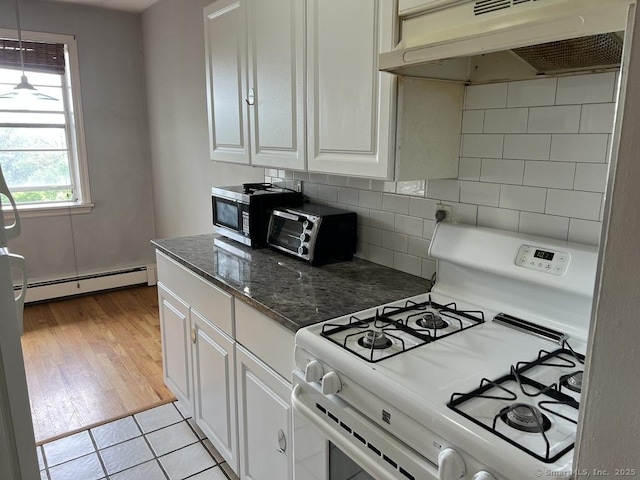 1 Walter Ave Apt 50, Norwalk, CT 06851 - kitchen with white gas stove, a baseboard heating unit, under cabinet range hood, decorative backsplash, and white cabinetry