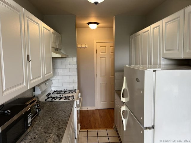 1 Walter Ave Apt 50, Norwalk, CT 06851 - kitchen featuring white appliances, under cabinet range hood, white cabinetry, backsplash, and dark stone countertops