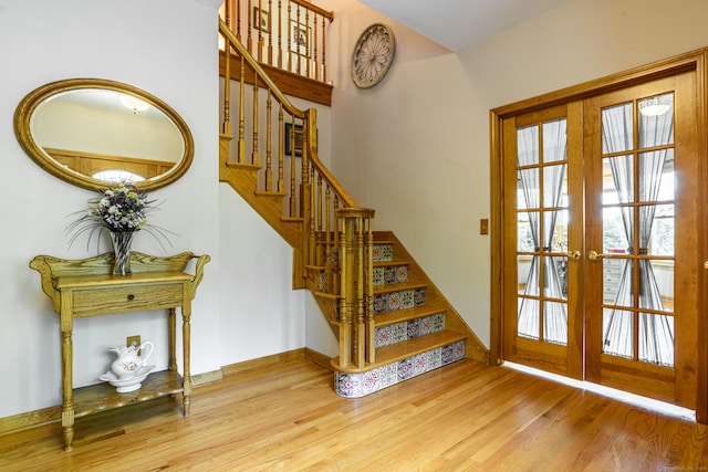 staircase with french doors, wood finished floors, and healthy amount of natural light