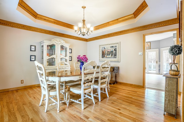 dining room featuring crown molding, a tray ceiling, a chandelier, light wood-type flooring, and baseboards