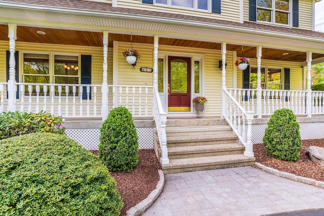 entrance to property with a porch and roof with shingles