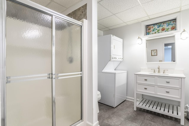 full bath with estacked washer and dryer, a drop ceiling, a stall shower, and vanity
