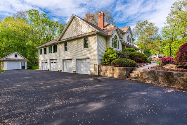 43 Roaring Brook Ln, Shelton, CT 06484 - view of home's exterior with a chimney, driveway, an attached garage, and an outbuilding