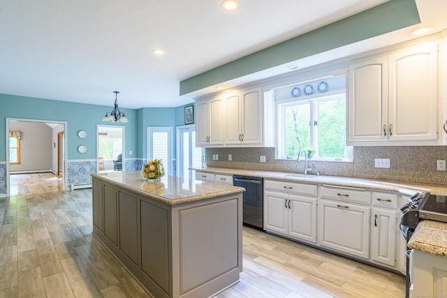 kitchen featuring dishwasher, a kitchen island, a sink, plenty of natural light, and recessed lighting