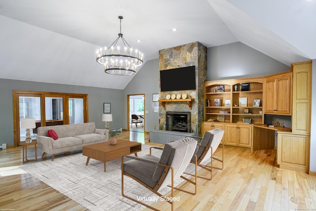 living area with light wood finished floors, high vaulted ceiling, a stone fireplace, and a chandelier