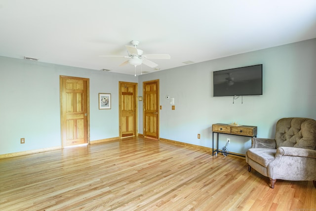 living room with light wood-type flooring, ceiling fan, and baseboards