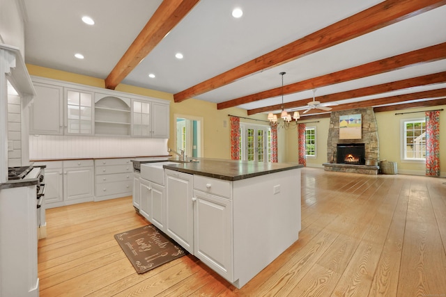 70 Sill Ln, Old Lyme, CT 06371 - kitchen with a sink, open shelves, dark countertops, a fireplace, and white cabinets