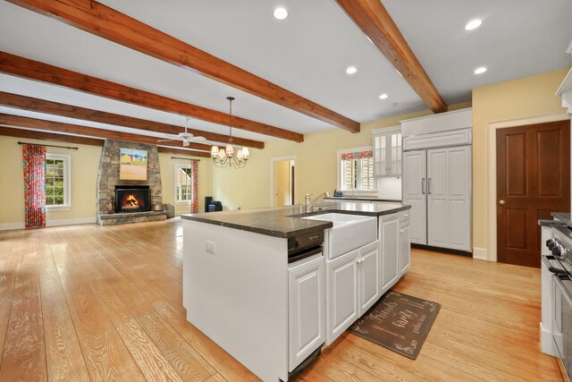 70 Sill Ln, Old Lyme, CT 06371 - kitchen featuring dark countertops, a fireplace, a kitchen island with sink, white cabinetry, and plenty of natural light