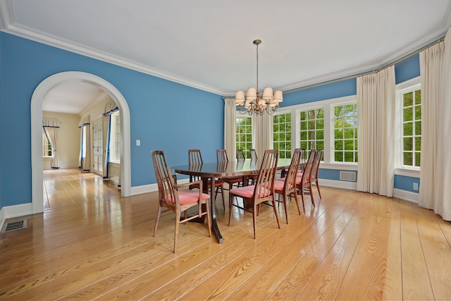 70 Sill Ln, Old Lyme, CT 06371 - dining space with arched walkways, a chandelier, light wood finished floors, crown molding, and baseboards