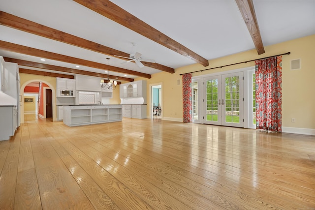 70 Sill Ln, Old Lyme, CT 06371 - unfurnished living room featuring baseboards, beamed ceiling, light wood-style floors, ceiling fan, and arched walkways