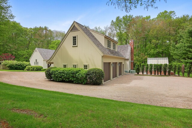 70 Sill Ln, Old Lyme, CT 06371 - view of side of property featuring gravel driveway, a chimney, a yard, and an attached garage