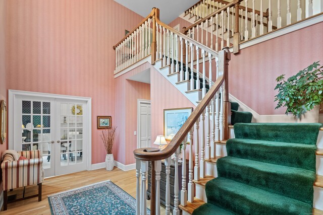 262 Fairview Rd, Westbrook, CT 06498 - stairway featuring french doors, wood finished floors, a towering ceiling, and baseboards