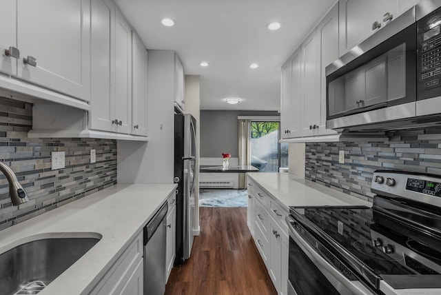 kitchen featuring appliances with stainless steel finishes, a sink, dark wood-style flooring, backsplash, and white cabinets