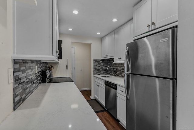 kitchen with stainless steel appliances, a sink, white cabinetry, backsplash, and dark wood-style floors