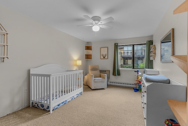 bedroom featuring baseboard heating, carpet, a nursery area, and a ceiling fan