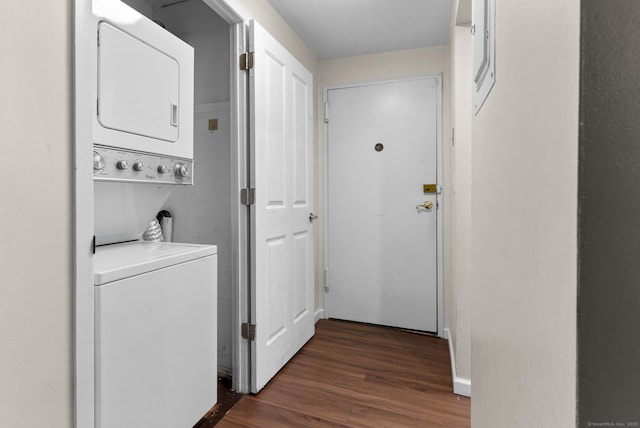 clothes washing area with stacked washer / dryer, dark wood-type flooring, and baseboards