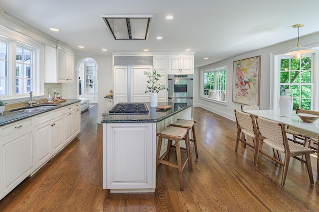 379 Hurlbutt St, Wilton, CT 06897 - kitchen featuring stainless steel gas cooktop, arched walkways, a kitchen island, paneled built in refrigerator, and a breakfast bar