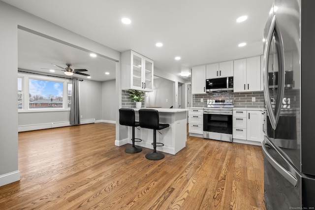 20 Rosengarten Dr, Waterbury, CT 06704 - kitchen with stainless steel appliances, a baseboard radiator, a kitchen bar, tasteful backsplash, and light countertops