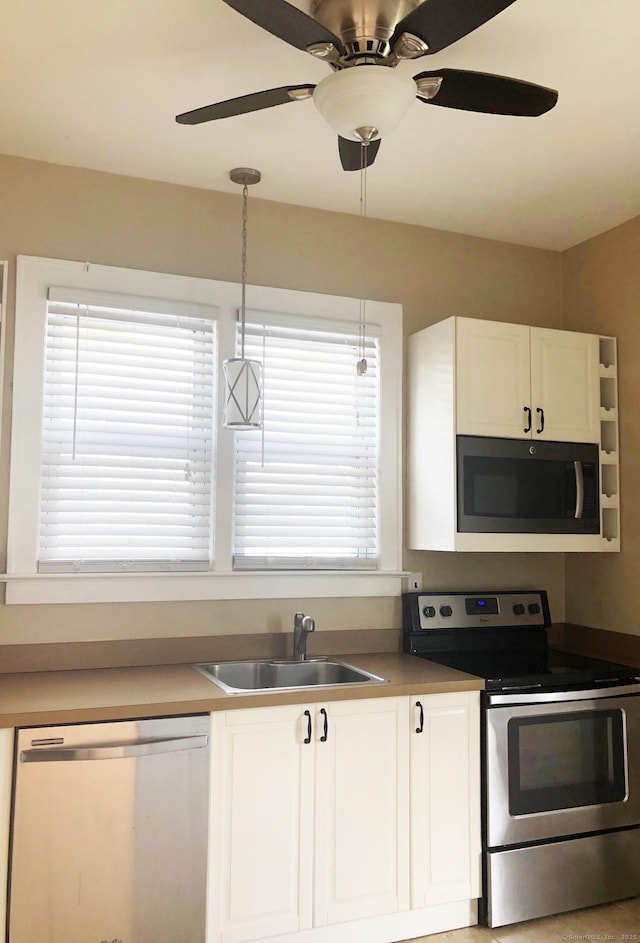 kitchen featuring appliances with stainless steel finishes, a sink, white cabinetry, and healthy amount of natural light