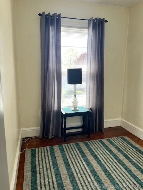 living area with plenty of natural light, dark wood-style floors, and baseboards