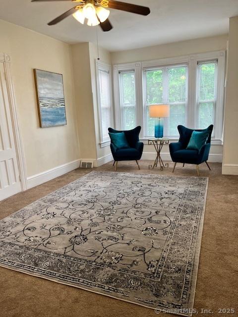 living area featuring a ceiling fan, plenty of natural light, carpet flooring, and baseboards