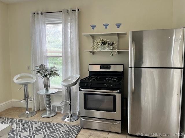 kitchen featuring stainless steel appliances, light tile patterned flooring, and baseboards