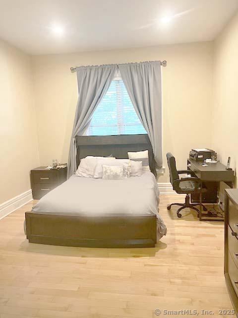 bedroom featuring light wood-type flooring, baseboards, and a desk