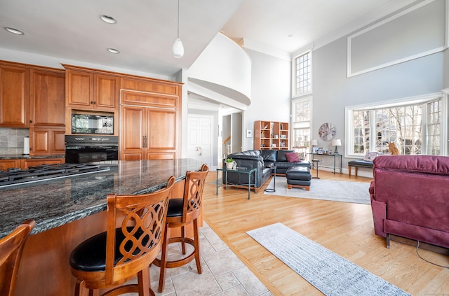 14 Dillman Ct, Ridgefield, CT 06877 - kitchen featuring black appliances, open floor plan, a kitchen bar, a high ceiling, and ornamental molding
