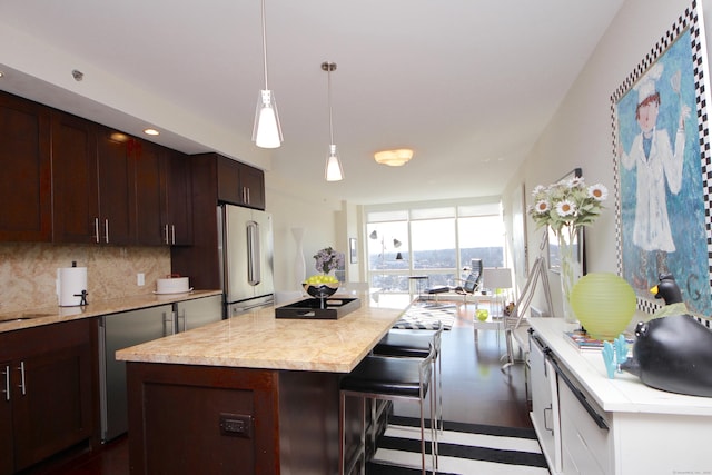 1 Broad St Unit 17C, Stamford, CT 06901 - kitchen featuring freestanding refrigerator, decorative backsplash, a kitchen breakfast bar, decorative light fixtures, and dark brown cabinetry