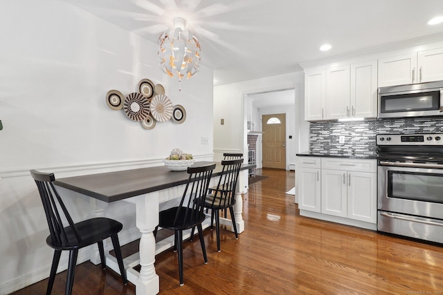 23 Poplar St, Norwalk, CT 06855 - kitchen with stainless steel appliances, tasteful backsplash, white cabinetry, dark countertops, and wood finished floors