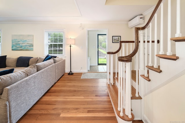 94 Mulberry St, Stamford, CT 06907 - foyer entrance with a wall unit AC, light wood-type flooring, crown molding, and stairs