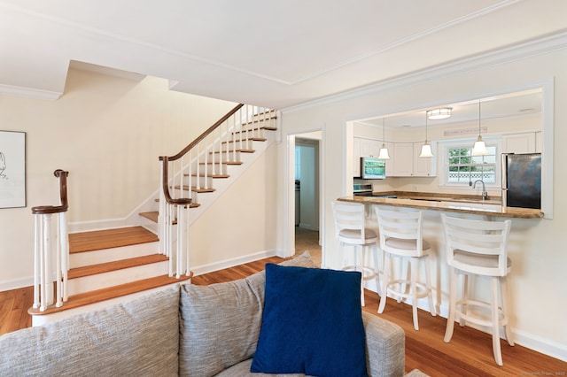 94 Mulberry St, Stamford, CT 06907 - kitchen with stainless steel appliances, white cabinets, a breakfast bar, crown molding, and wood finished floors