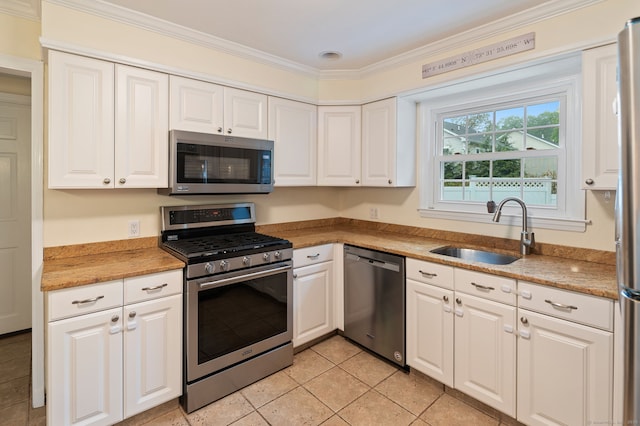 94 Mulberry St, Stamford, CT 06907 - kitchen with appliances with stainless steel finishes, white cabinets, light tile patterned floors, and ornamental molding