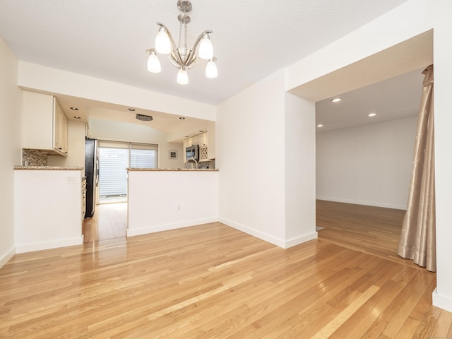 24 Wilton Crst Unit 24, Wilton, CT 06897 - unfurnished living room featuring light wood finished floors, a chandelier, and baseboards