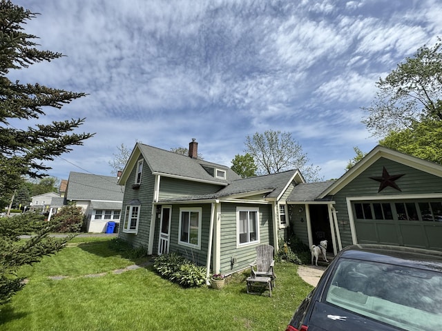 traditional-style house featuring an attached garage, a front yard, a chimney, and roof with shingles