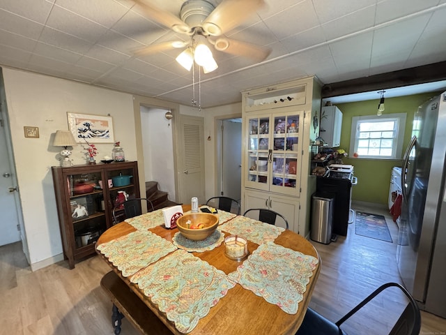 dining room with light wood-type flooring, a ceiling fan, stairway, and baseboards