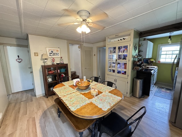dining area featuring light wood-style flooring, a ceiling fan, and baseboards