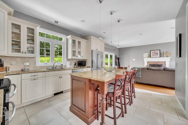 27 Regency Dr, North Haven, CT 06473 - kitchen featuring stainless steel appliances, a sink, open floor plan, light stone counters, and a brick fireplace