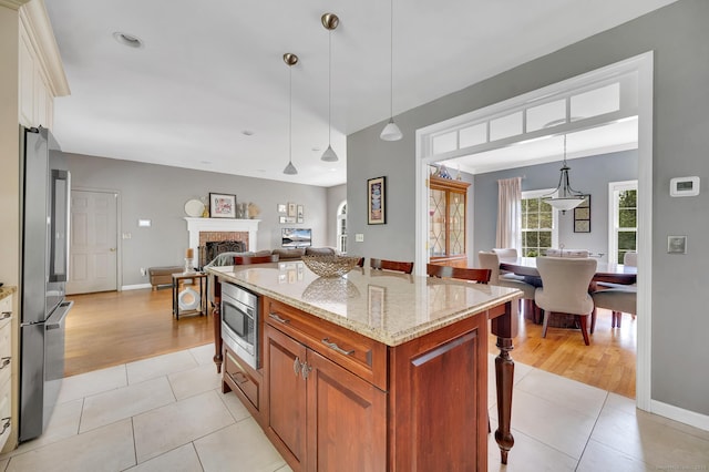27 Regency Dr, North Haven, CT 06473 - kitchen featuring stainless steel appliances, a kitchen breakfast bar, brown cabinetry, and light tile patterned floors