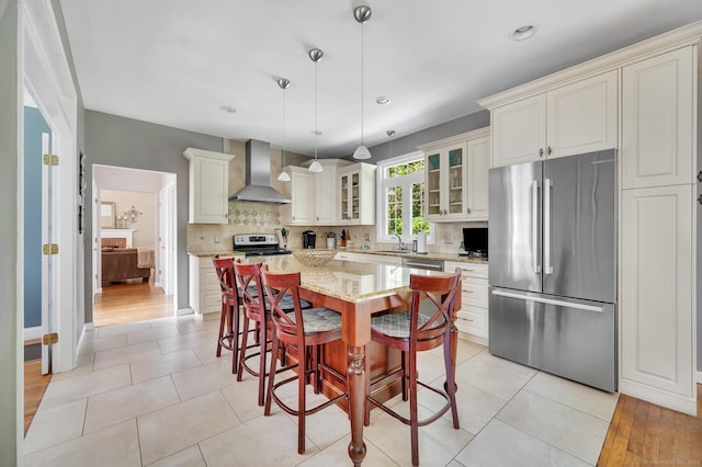 27 Regency Dr, North Haven, CT 06473 - kitchen featuring freestanding refrigerator, wall chimney exhaust hood, a sink, glass insert cabinets, and light stone countertops