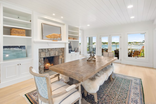 dining room with light wood finished floors, a stone fireplace, wooden ceiling, built in features, and recessed lighting