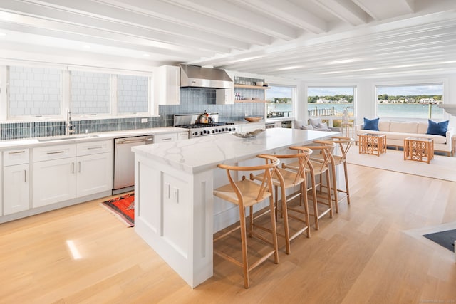kitchen featuring dishwasher, a sink, wall chimney exhaust hood, range, and backsplash